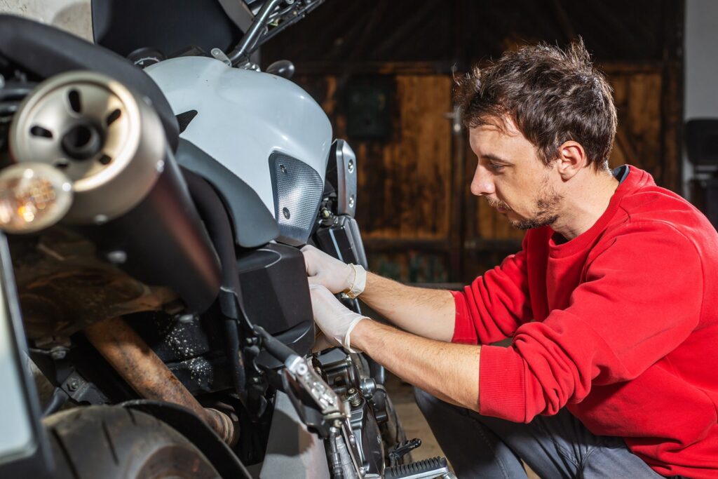 Giovane uomo che prepara la moto per la stagione invernale